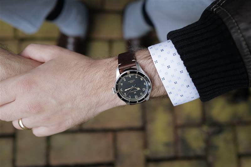 38 毫米尺寸的 Hamilton Khaki Pilot Pioneer 手腕交叉佩戴棕色皮夾克。